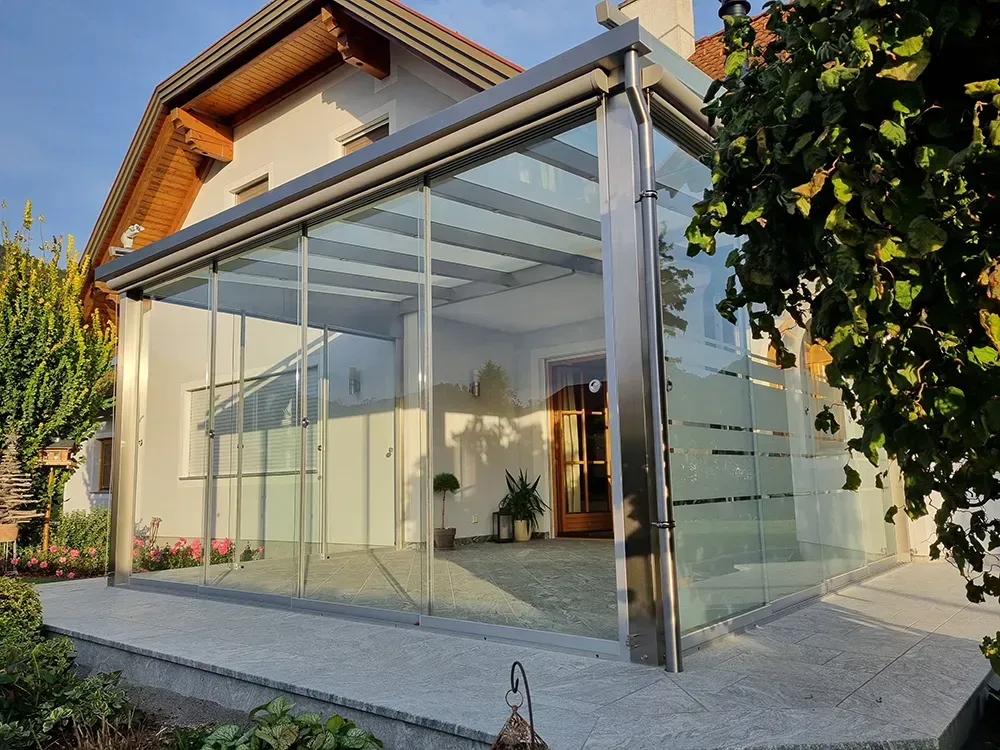 Ein Haus mit einer glasüberdachten Veranda davor.