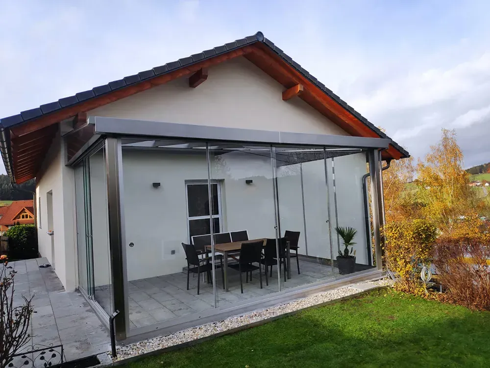 Ein Haus mit einer Terrasse mit einem Tisch und Stühlen darauf.
