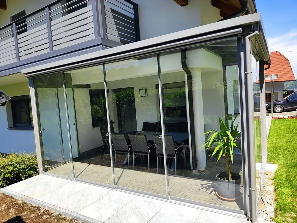 Vor einem Haus gibt es eine Terrasse mit Tisch und Stühlen.