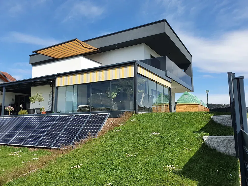 Ein modernes Haus mit Solarmodulen auf der Wiese davor.