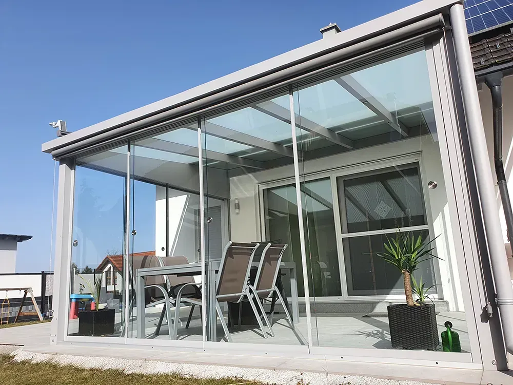 Eine Terrasse mit Tisch und Stühlen unter einem Glasdach.