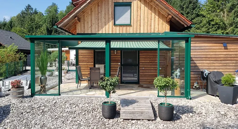 Ein Holzhaus mit einer grünen Veranda und einer grünen Markise