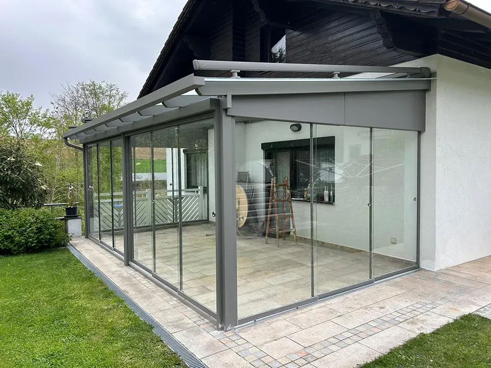 Ein Haus mit einer Terrasse mit Glasschiebetüren und einem Dach.