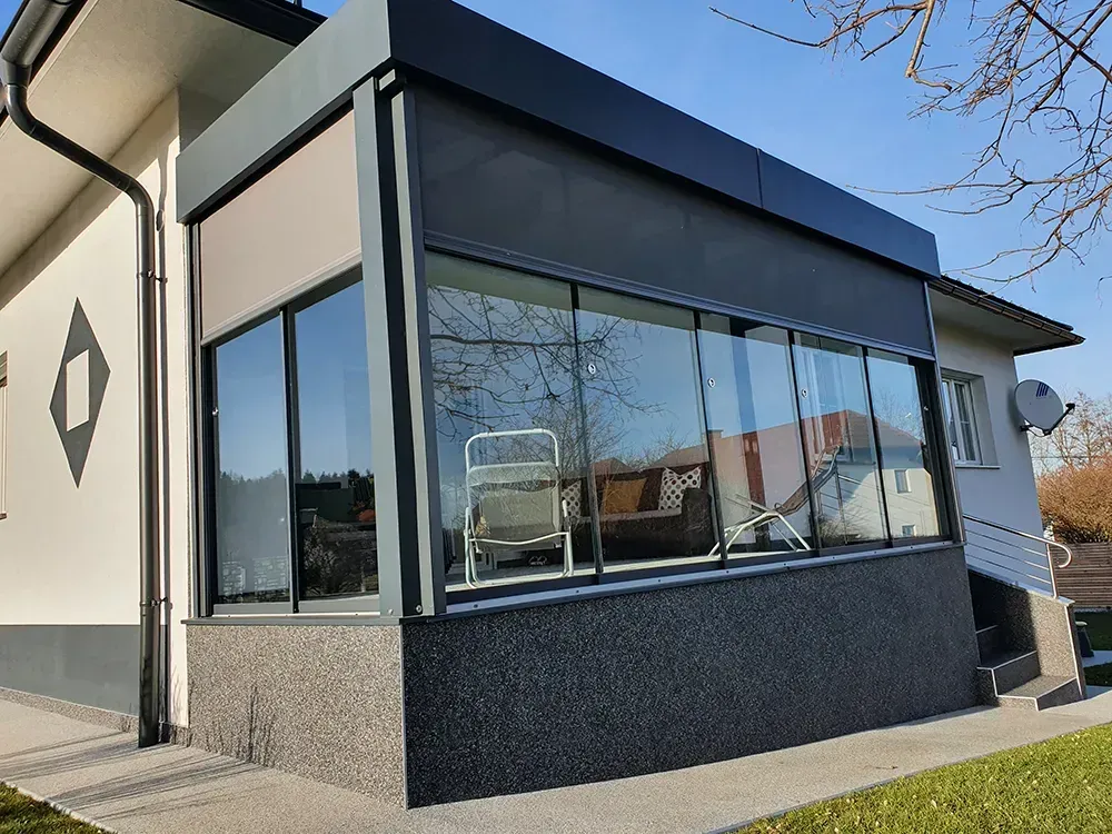 Ein Haus mit vielen Fenstern und einem Stuhl auf der Veranda.