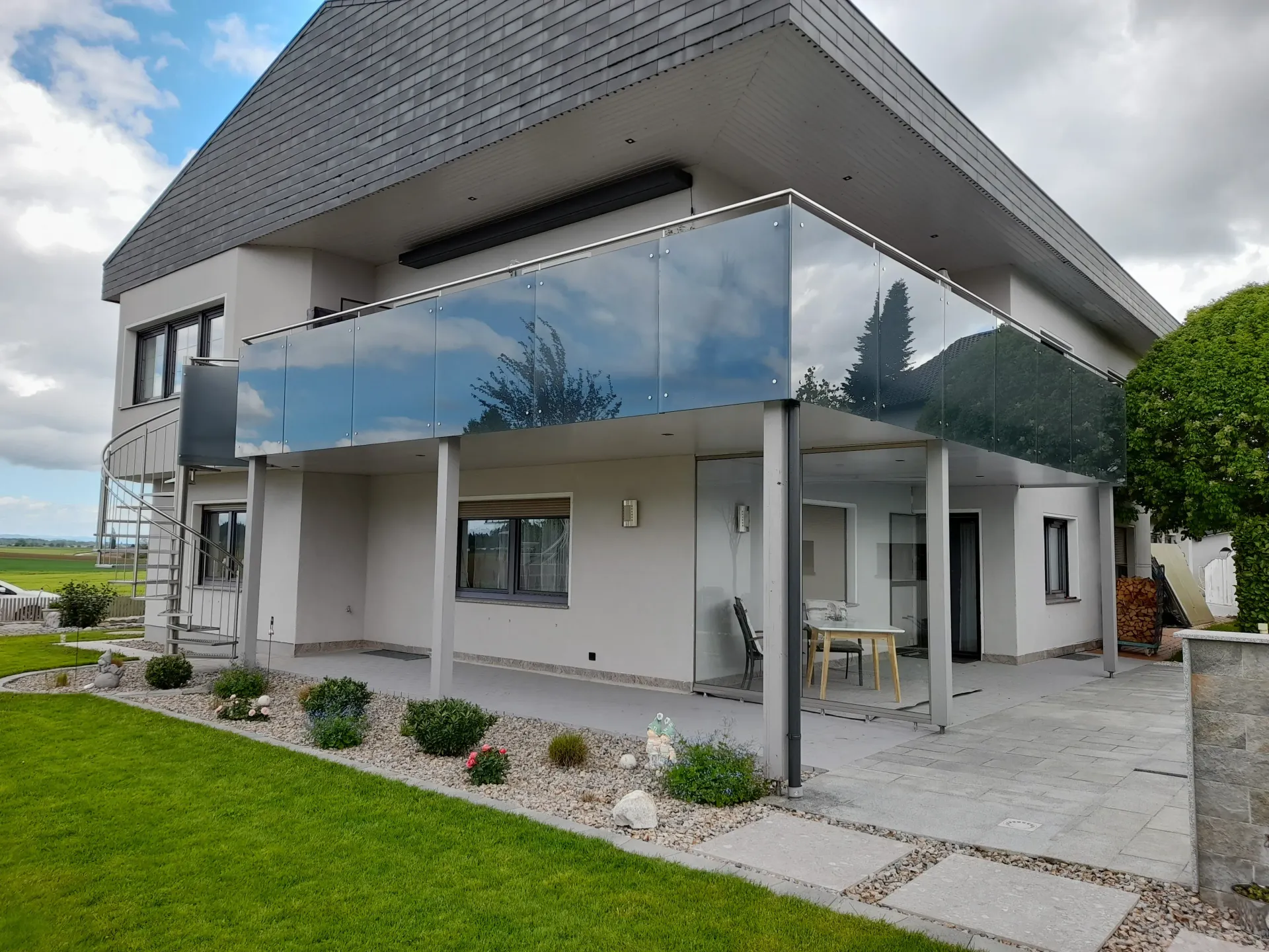 Ein großes weißes Haus mit einem Glasbalkon an der Seite.