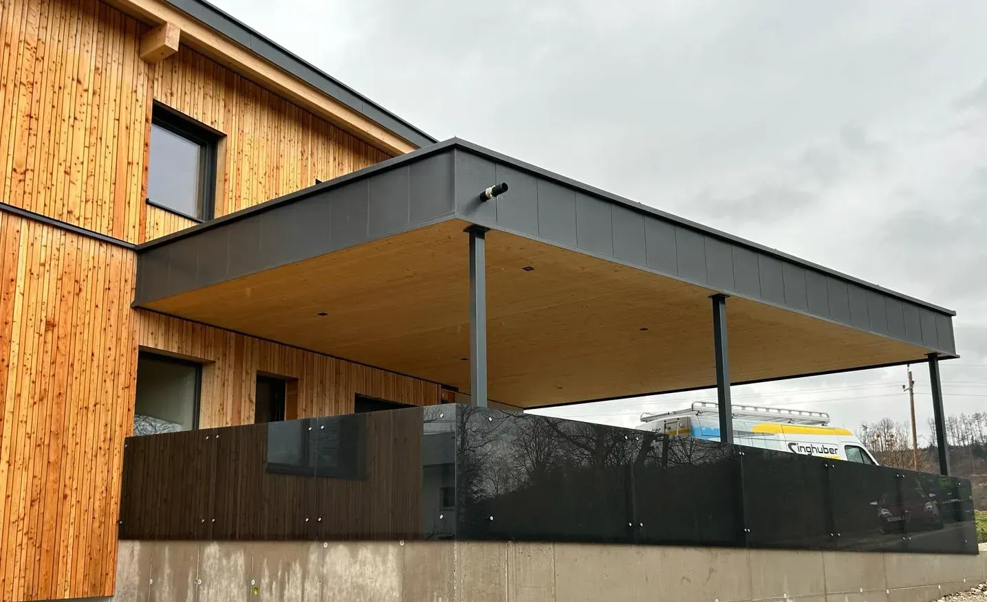 Ein Holzhaus mit einer großen Veranda und einem schwarzen Zaun.