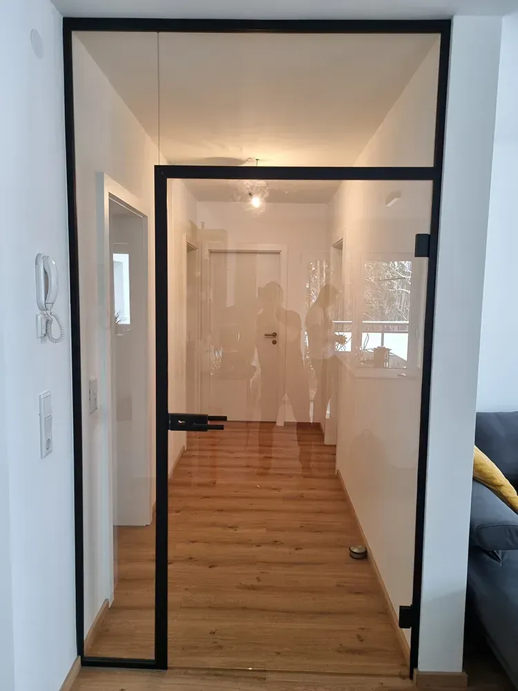 Ein Flur mit einer Glastür und einem schwarzen Rahmen.