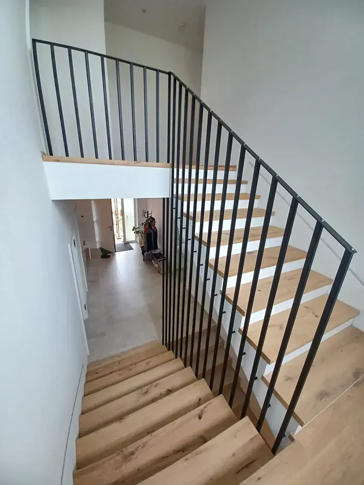 Eine Holztreppe mit einem Metallgeländer in einem Haus.