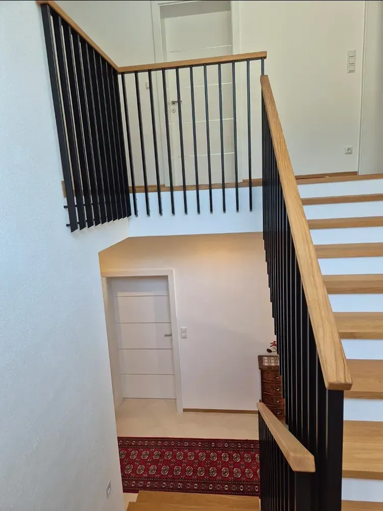 Eine Treppe mit schwarzem Geländer und Holzstufen