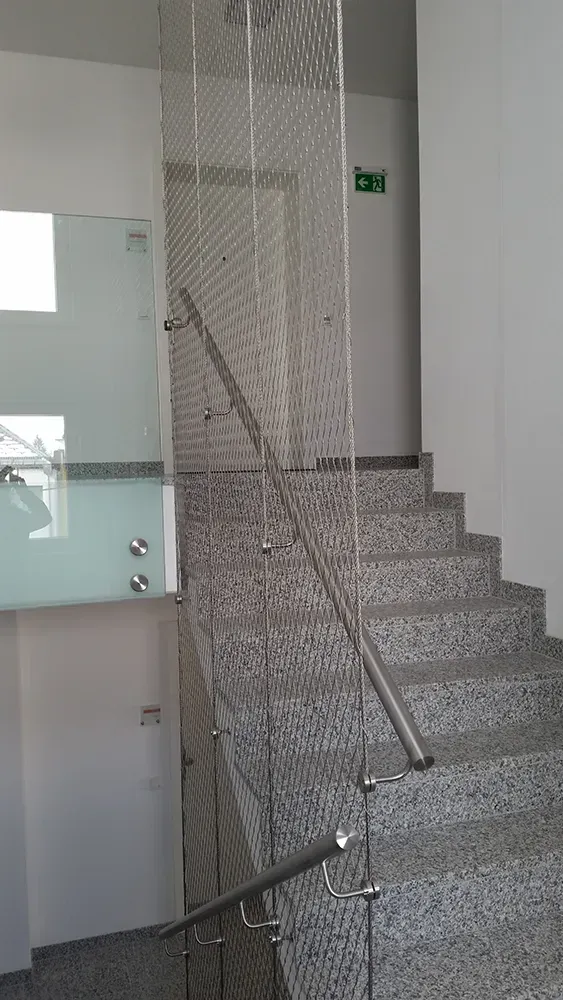 Eine Treppe mit einem Glasgeländer und einem Edelstahlgeländer in einem Gebäude.
