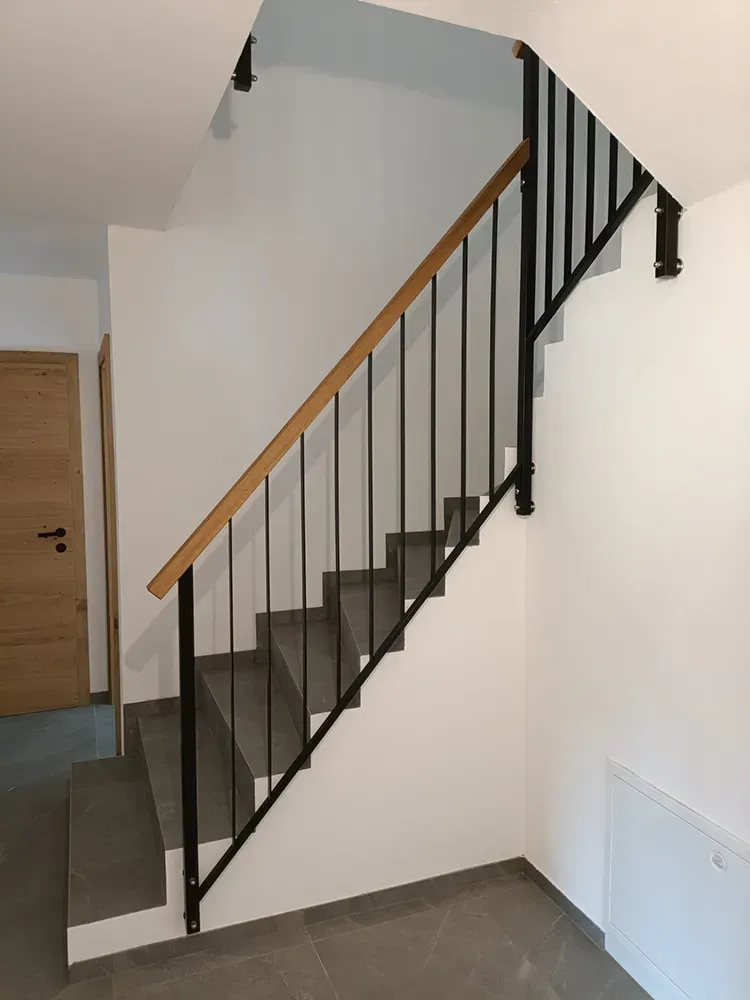Eine Treppe mit schwarzem Geländer und Holzhandlauf