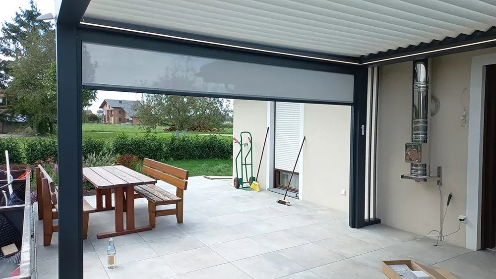 Eine Terrasse mit Tisch und Bank unter einer Pergola.