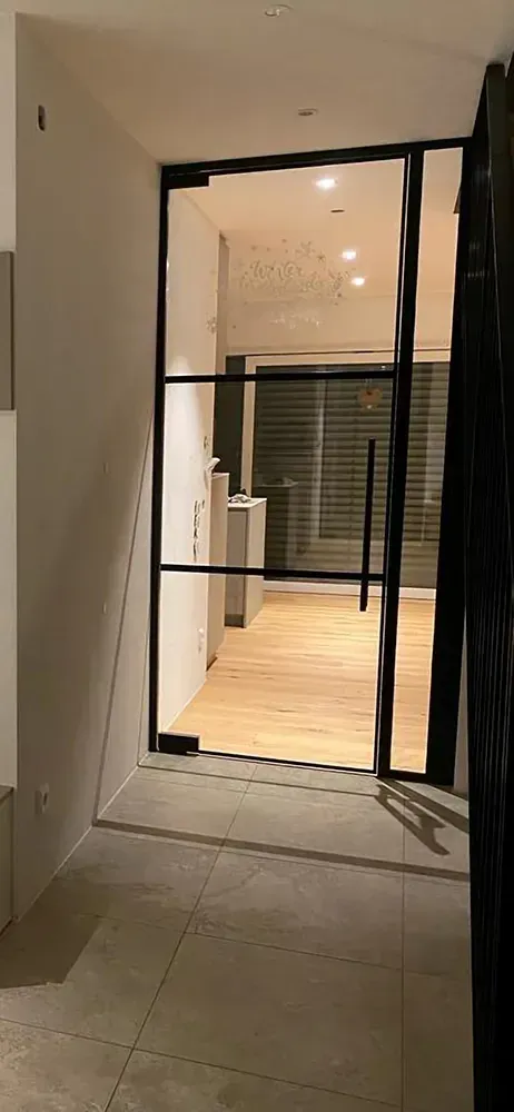 Ein Flur mit Glastür und Holzboden.