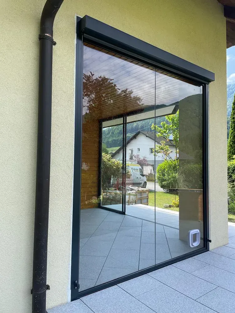 An der Seite eines Gebäudes befindet sich ein großes Fenster mit Glasschiebetüren.