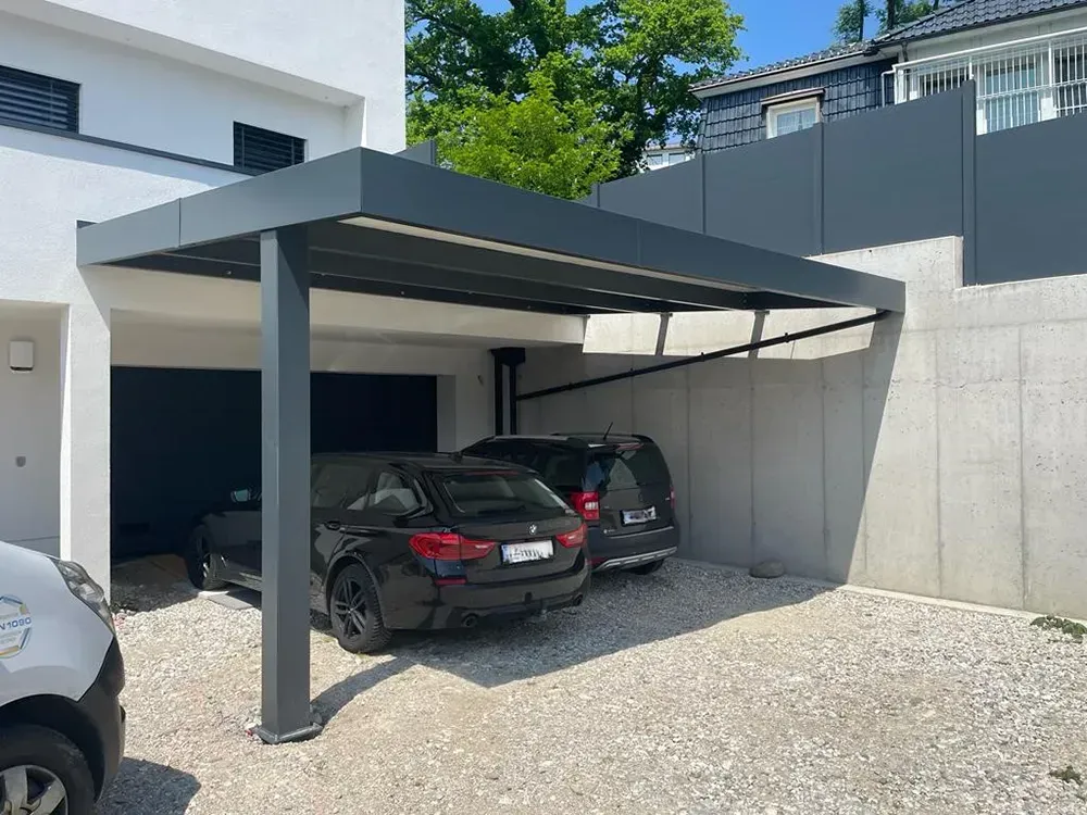 Zwei Autos sind unter einem Carport vor einem Haus geparkt.