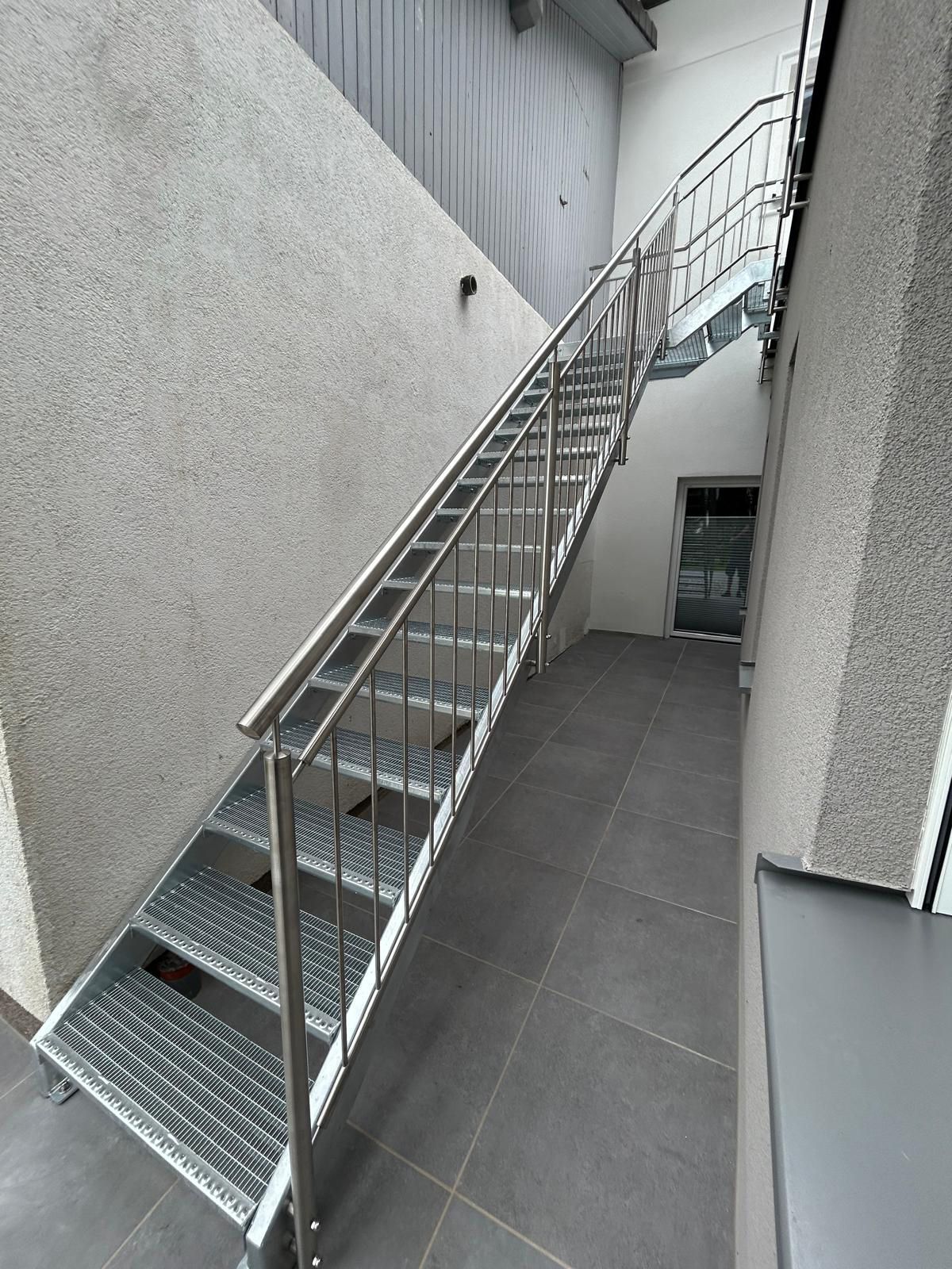 Eine Treppe mit Edelstahlgeländer führt in den zweiten Stock eines Gebäudes.