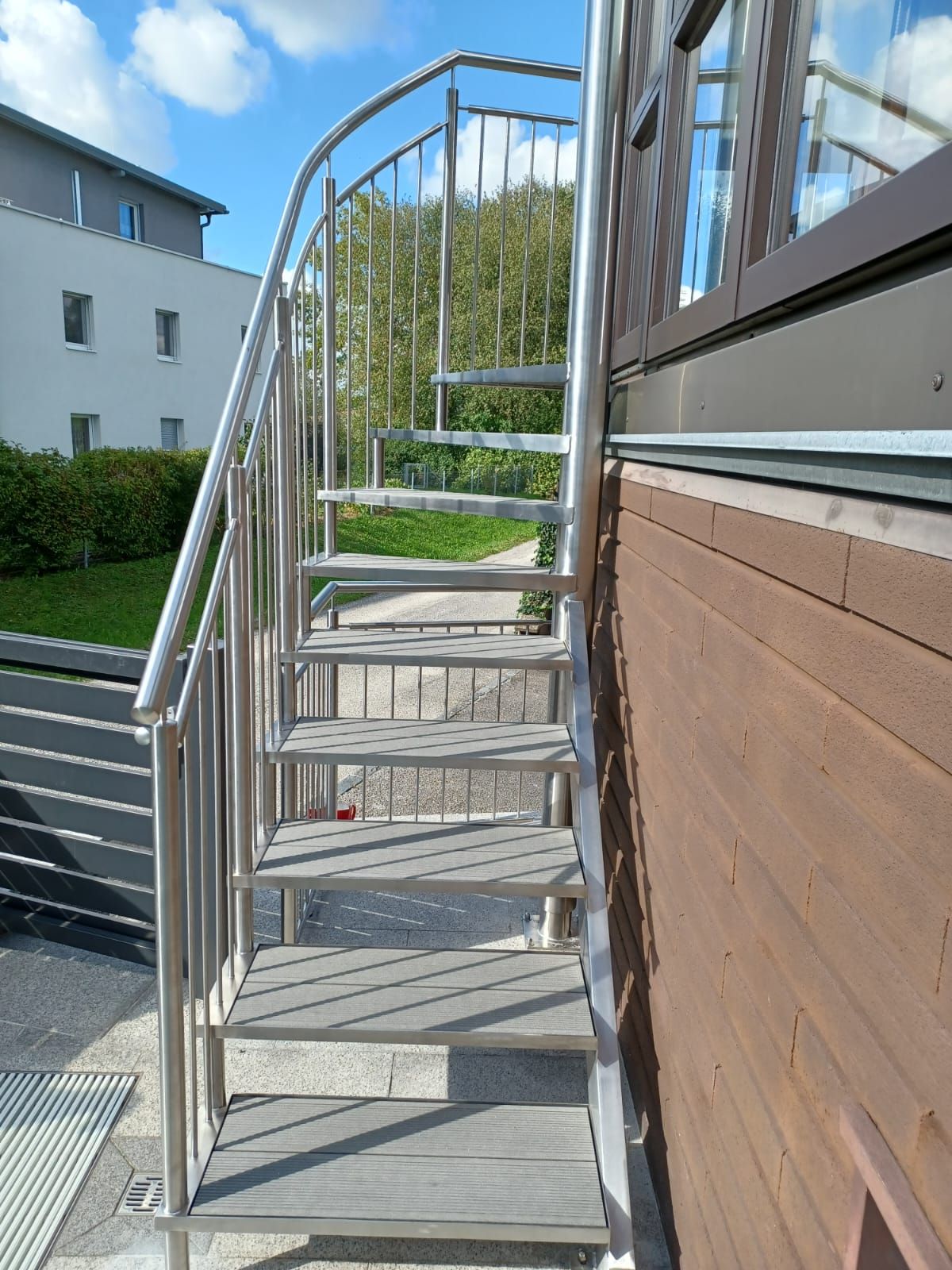 Eine Wendeltreppe mit einem Edelstahlgeländer an der Seite eines Gebäudes