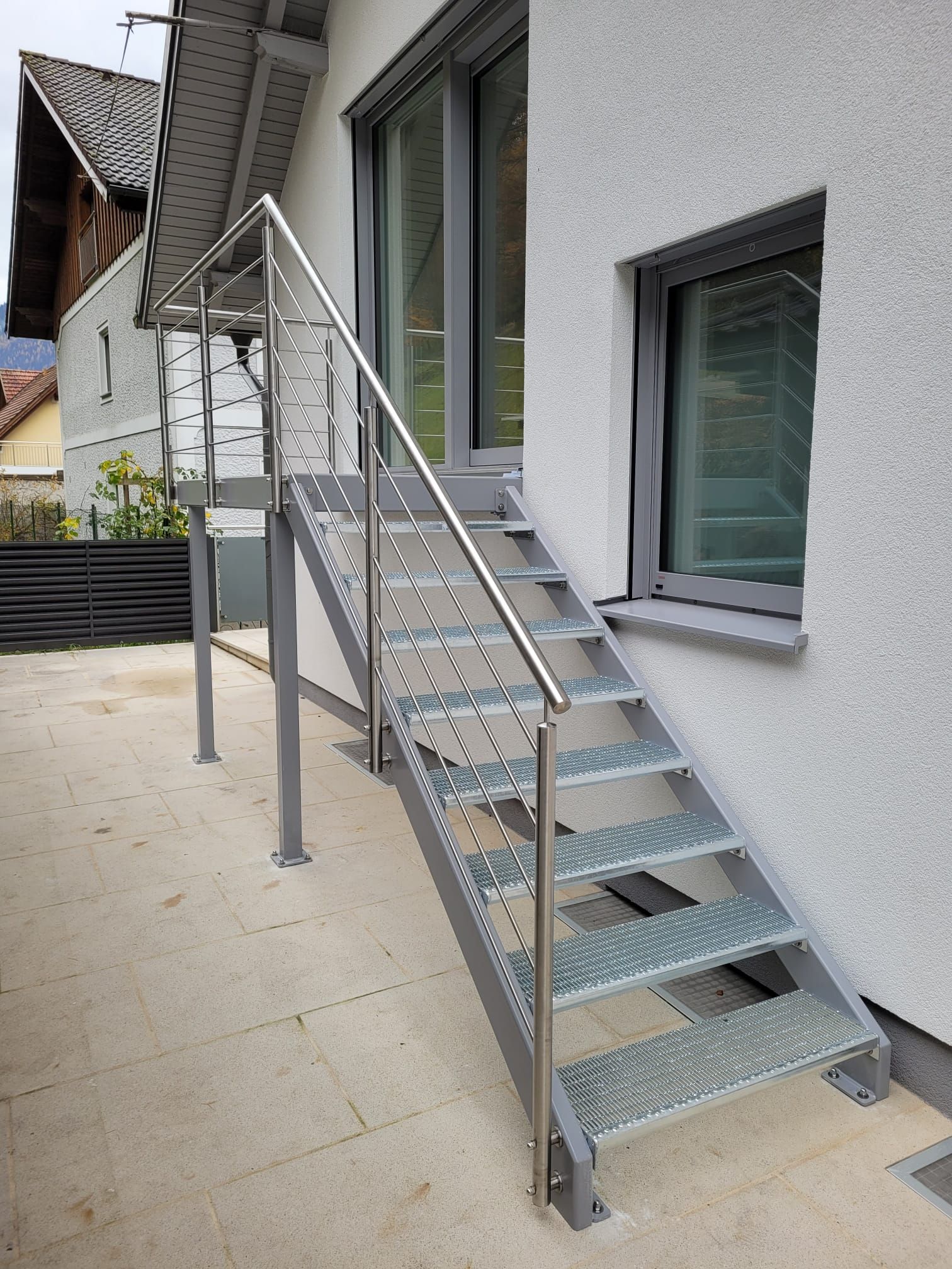 Eine Treppe mit einem Edelstahlgeländer an der Seite eines Gebäudes.