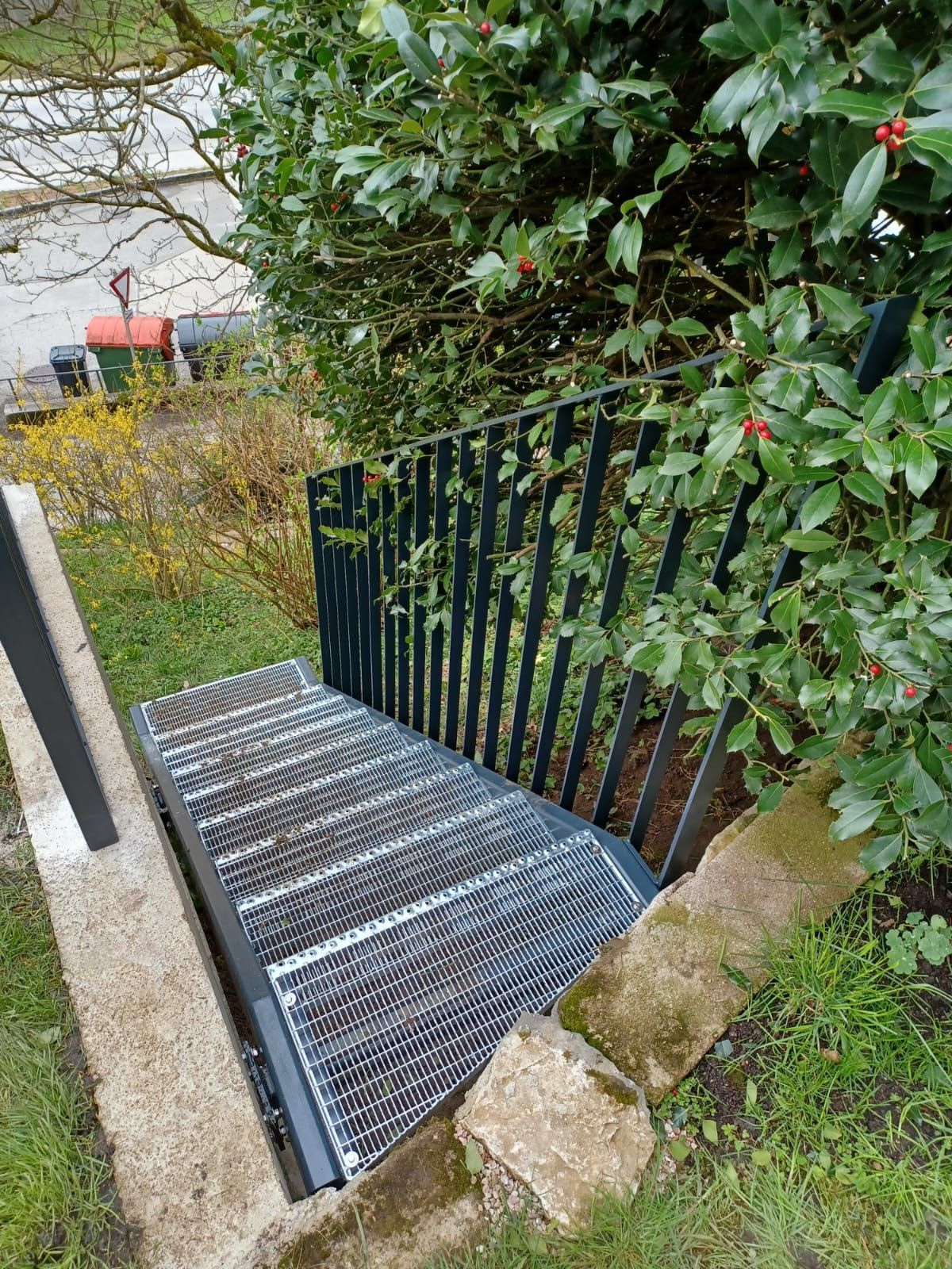 Eine Metalltreppe, die zu einem Baum in einem Garten führt.