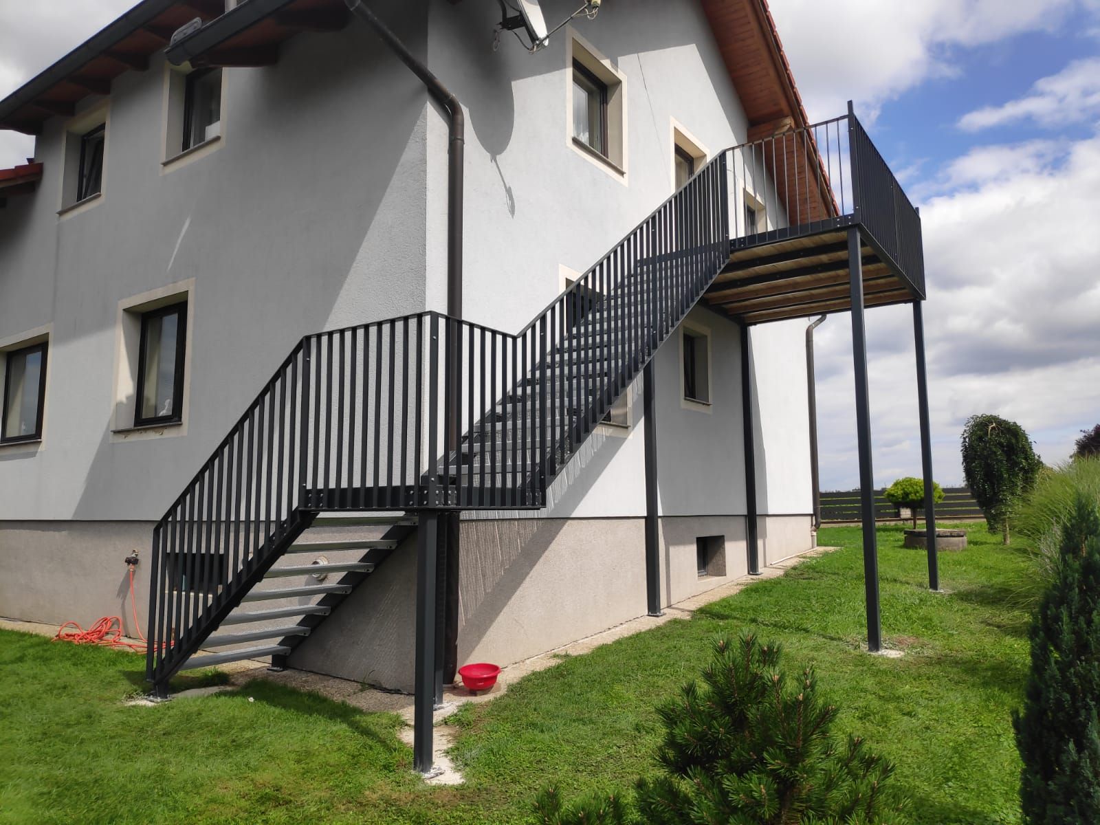 Ein weißes Haus mit einer Treppe, die zu einem Balkon führt.