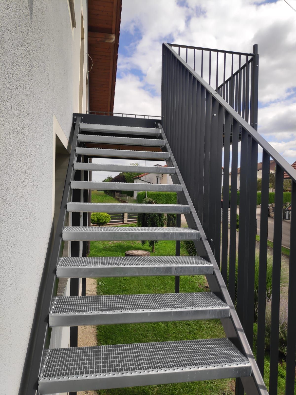 Eine Treppe mit Edelstahlgeländer führt in den zweiten Stock eines Gebäudes.