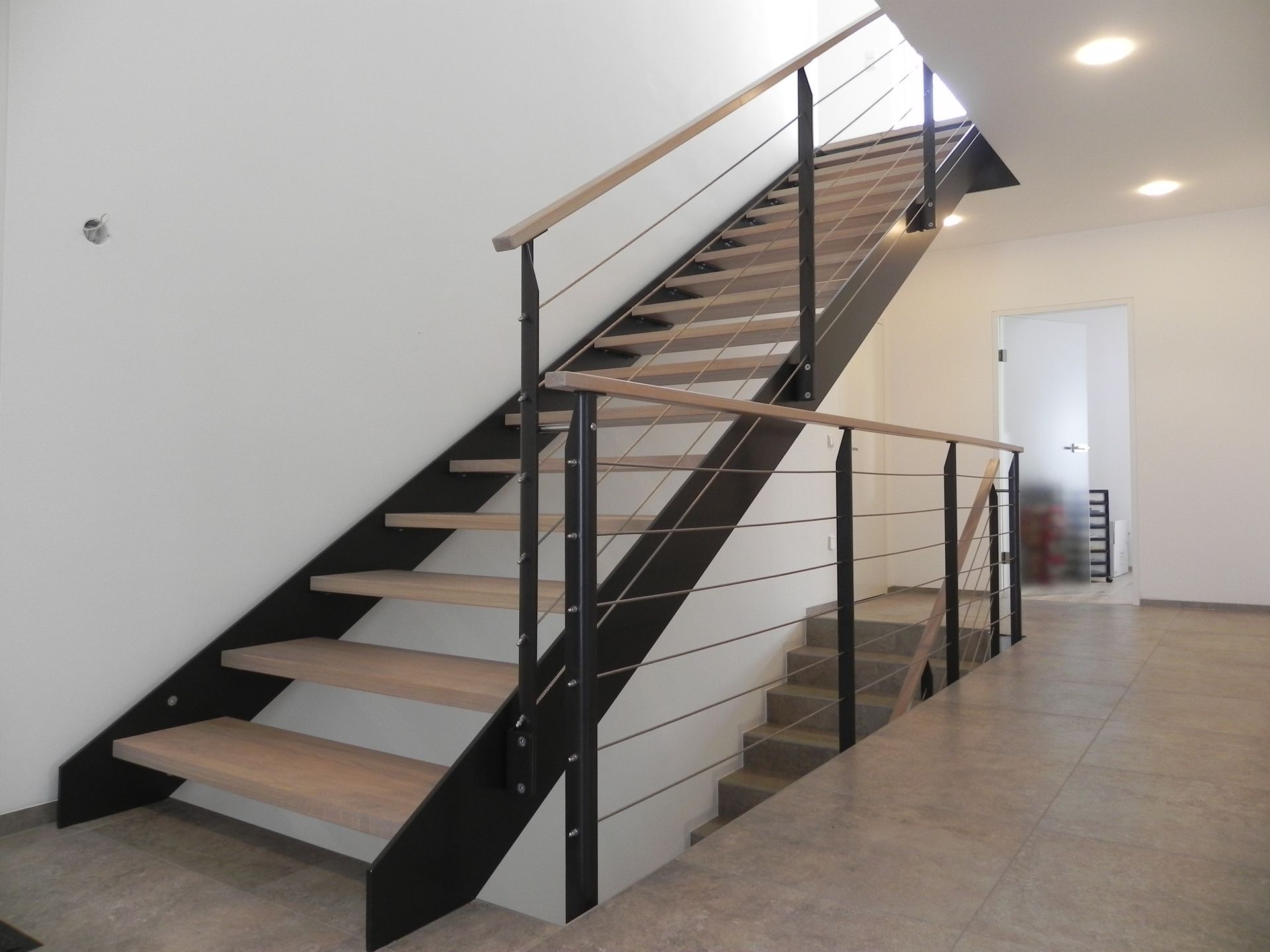 Eine Treppe mit schwarzem Geländer und Holzstufen