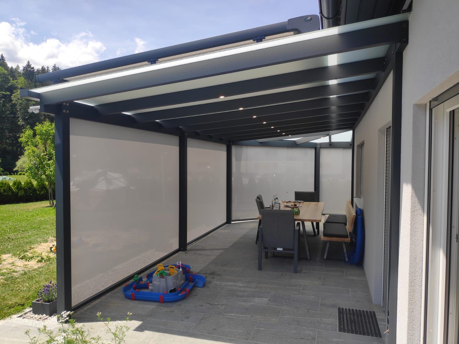 Eine Terrasse mit Tisch und Stühlen unter einem Baldachin.