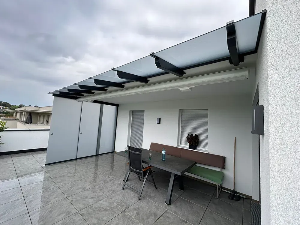 Auf dem Dach eines Gebäudes stehen ein Tisch und Stühle.