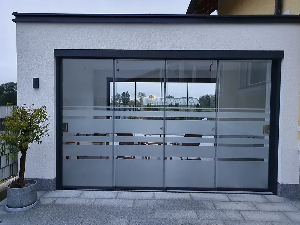 Ein Haus mit einer Glasschiebetür, die wie ein Garagentor aussieht