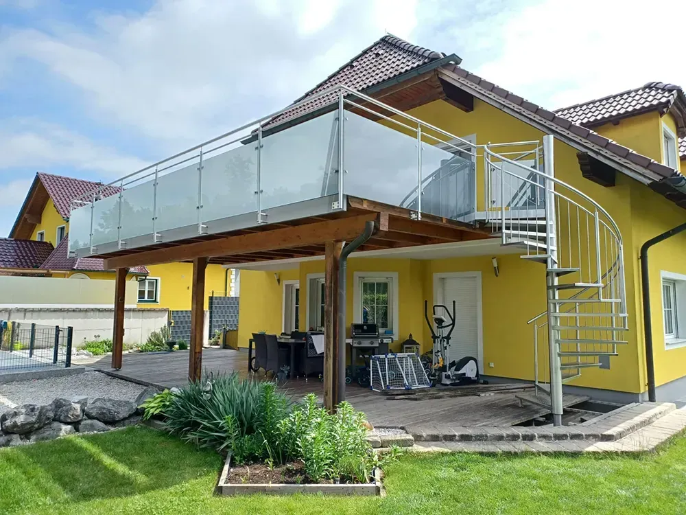 Ein gelbes Haus mit einer Wendeltreppe und einem Balkon.