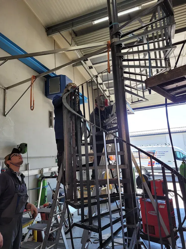 Eine Gruppe von Leuten arbeitet an einer Wendeltreppe in einem Gebäude.