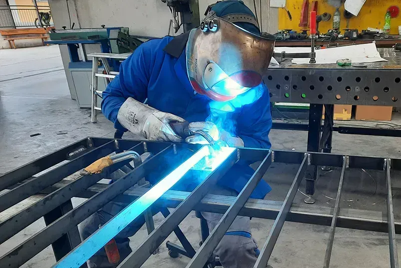 Ein Mann mit einer Schweißmaske schweißt ein Stück Metall.