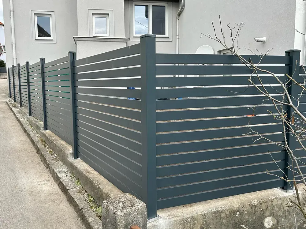 Ein Zaun umgibt ein Haus am Straßenrand.