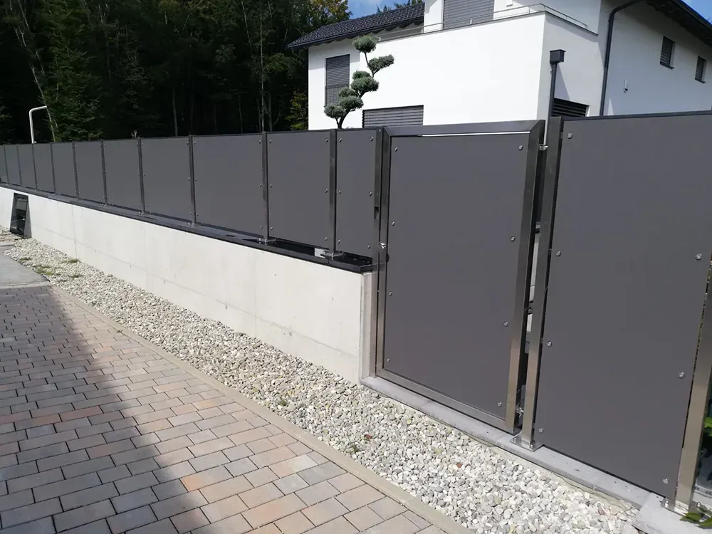 Ein Zaun mit einem Tor vor einem Haus