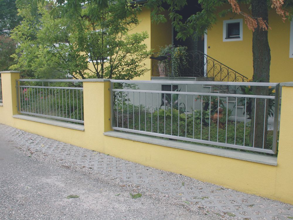 Ein gelbes Haus mit einem Metallzaun davor