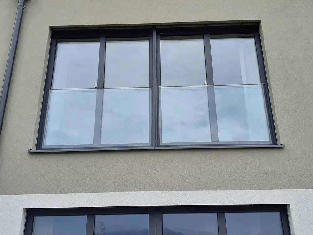 Ein großes Fenster an der Seite eines Gebäudes mit einem Glasgeländer.