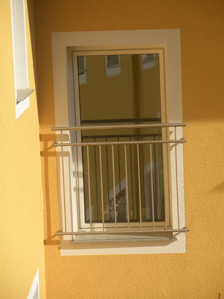 Ein Fenster mit einem Metallgeländer an der Seite eines Gebäudes