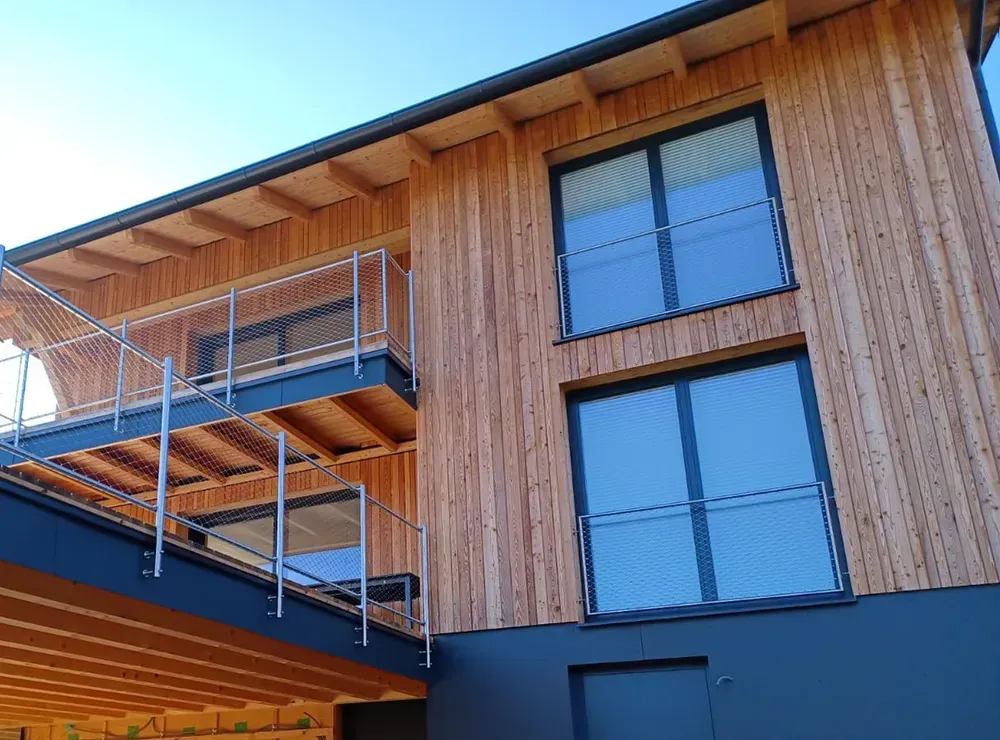Ein Holzhaus mit Balkon und vielen Fenstern.