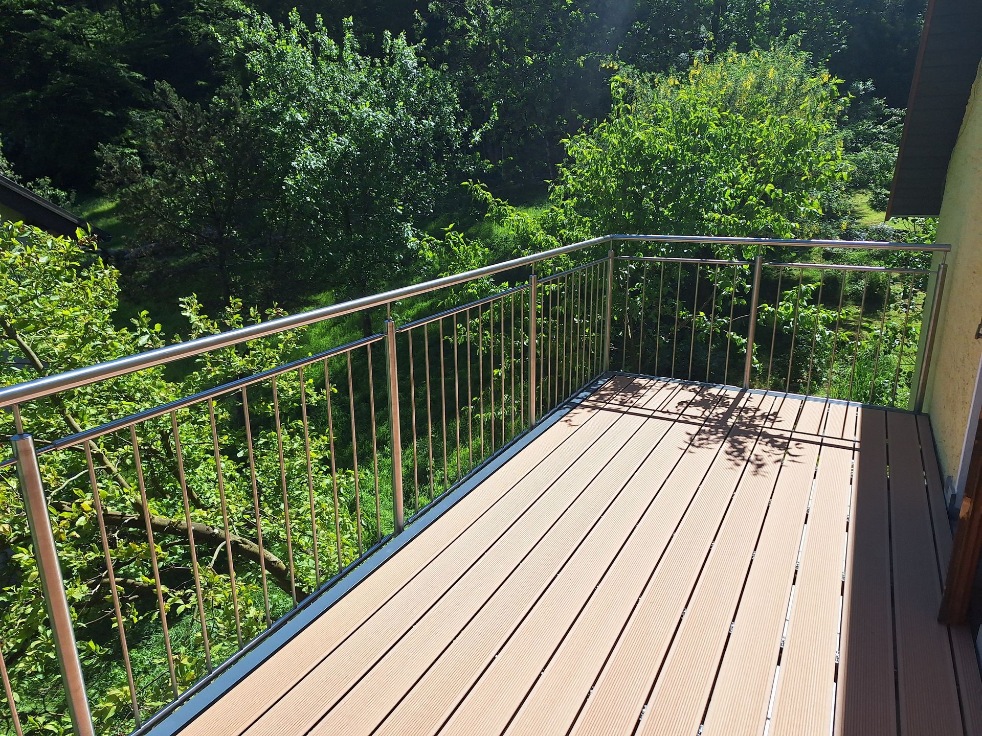 Ein Balkon mit Edelstahlgeländer und Holzterrasse
