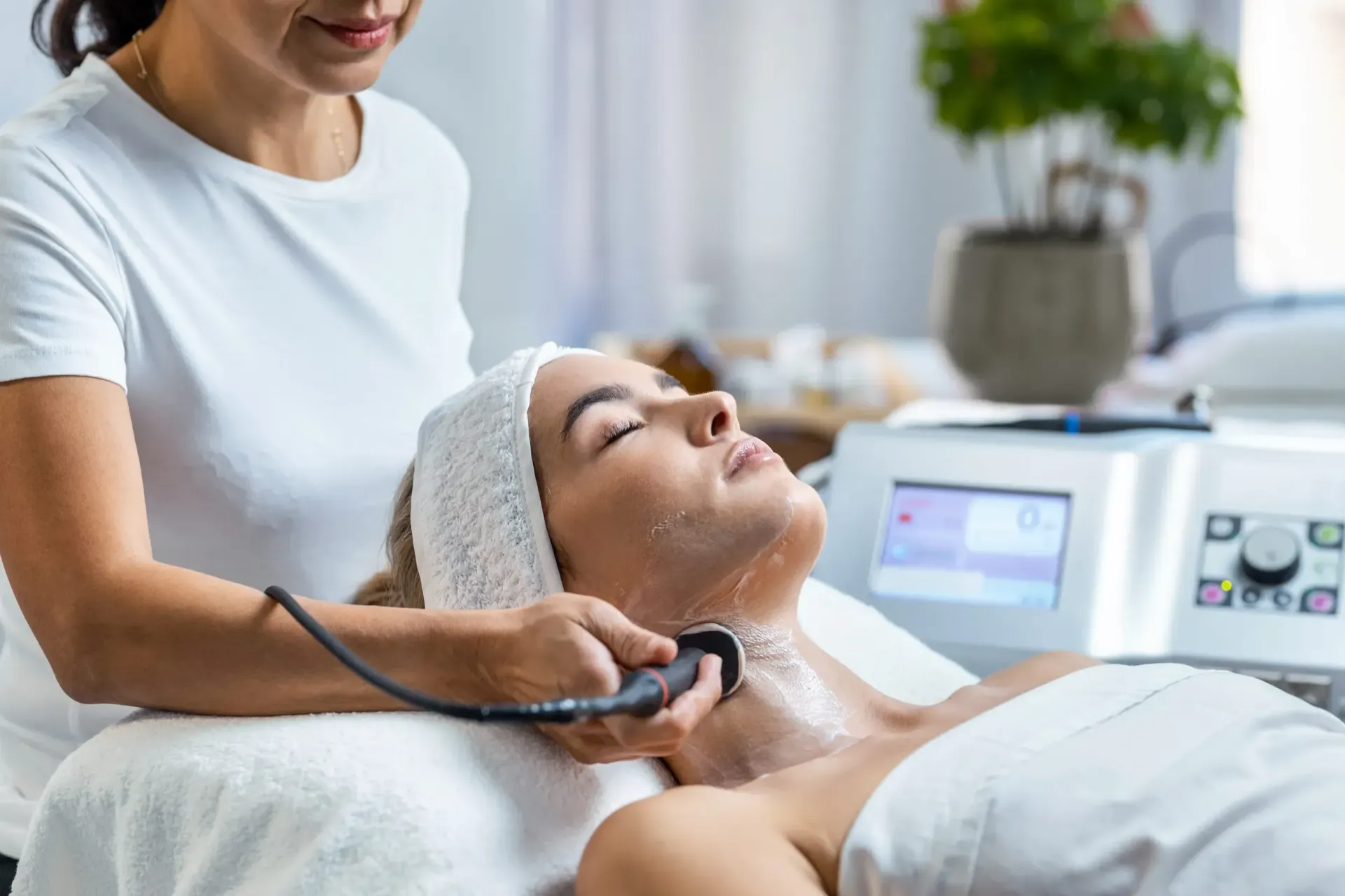 Un profesional realiza un tratamiento facial a una persona tumbada utilizando un dispositivo estético 