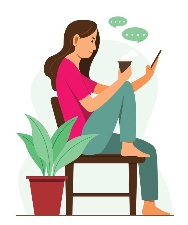 Una mujer está sentada en una silla mirando su teléfono celular.