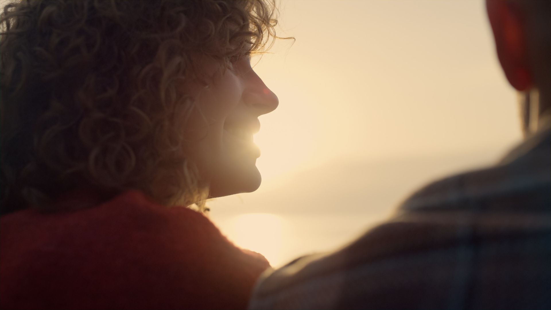 Un hombre y una mujer se miran frente a una puesta de sol.