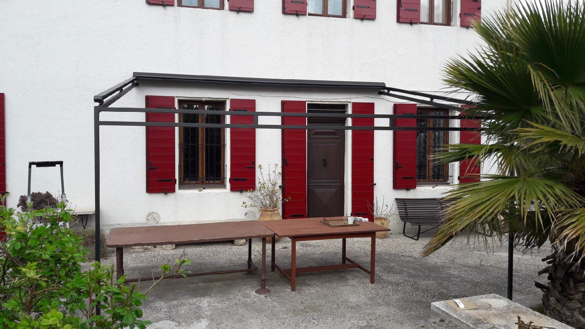Façade de maison avec une table protégée par une tonnelle