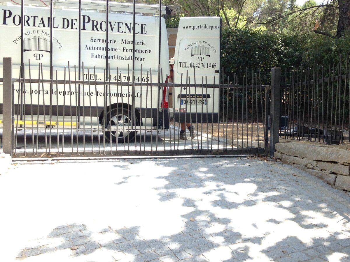 Portail acier gris devant la camionnette de l'entreprise