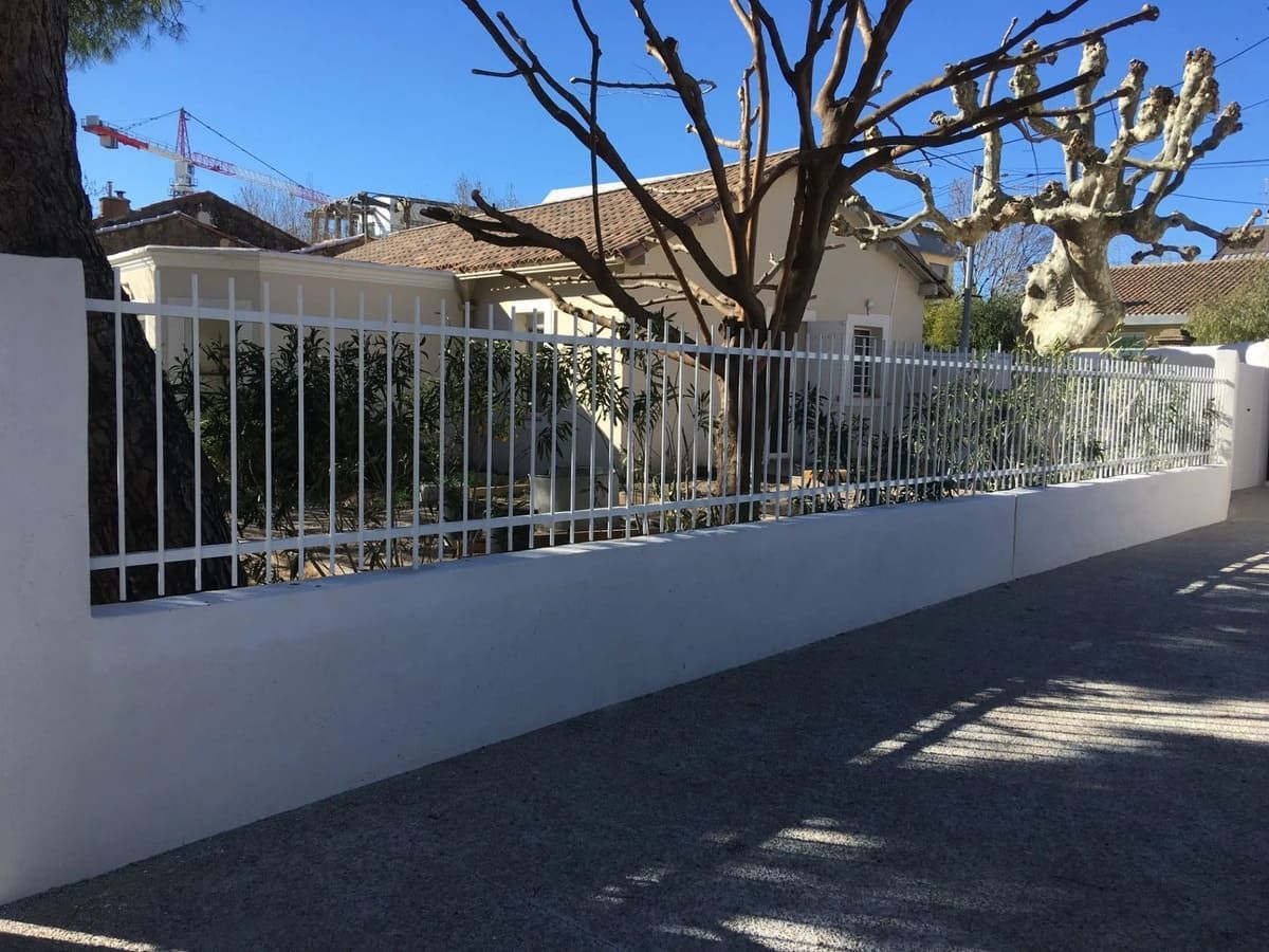 Une clôture blanche au-dessus d'un muret