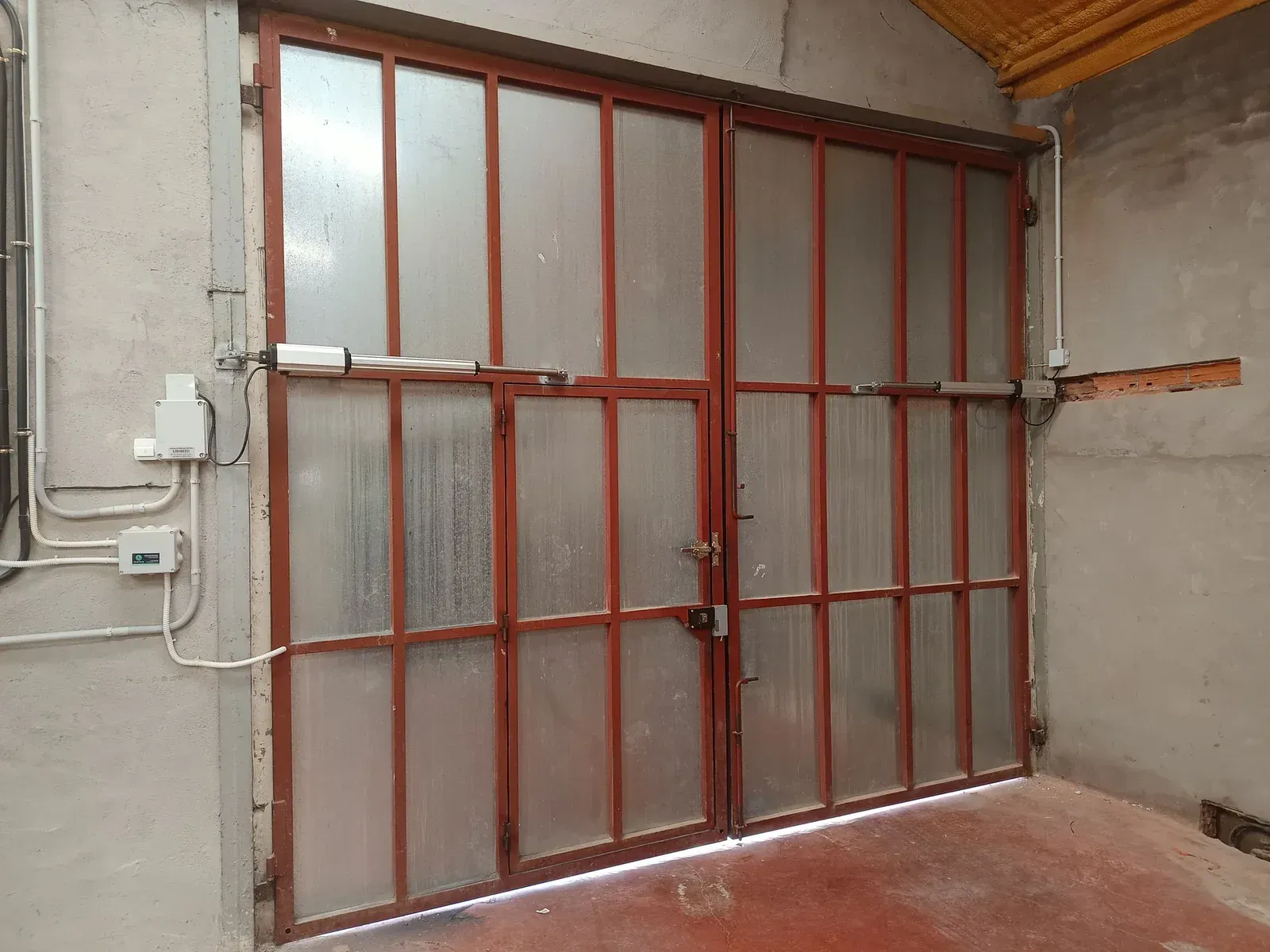 Puertas de almacén cerradas de metal rojo con paneles de vidrio esmerilado.