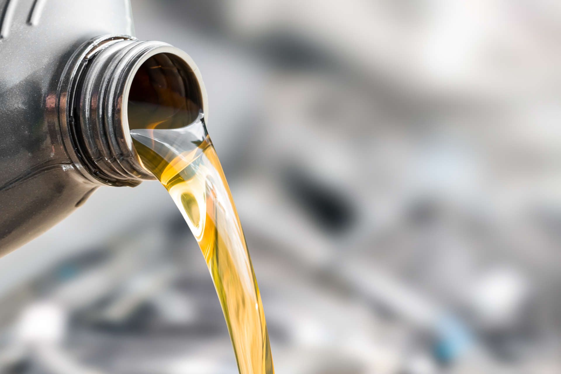 Eine Flasche Öl wird in einen Automotor gegossen.