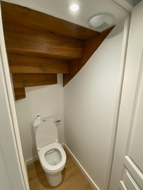 Toilettes avec les murs blancs et le parquet.