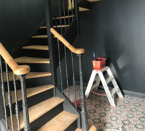Un escalier en bois et les murs noirs.