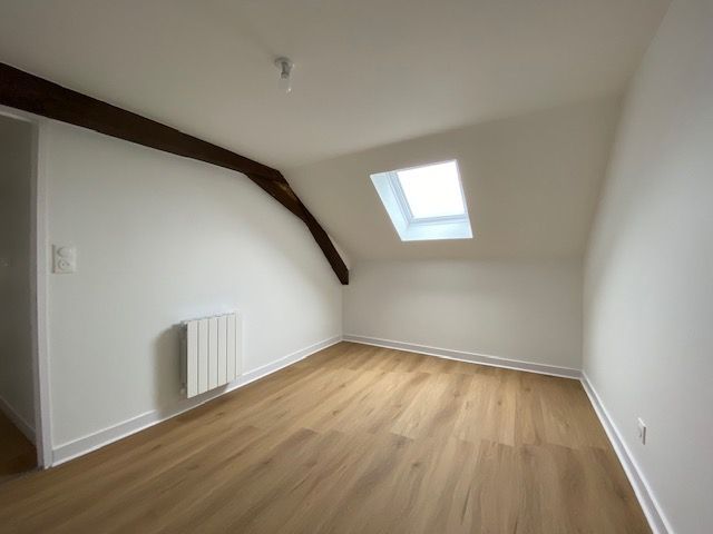 Une pièce sous le toit avec les murs blancs et une poutre.